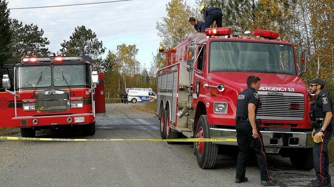 A police officer unfurls police tape to secure the scene of a house fire on Potvin Crescent this morning. Greater Sudbury Police have confirmed that the body of a 48-year-old man was found following a house fire this morning. (Arron Pickard/Sudbury.com)