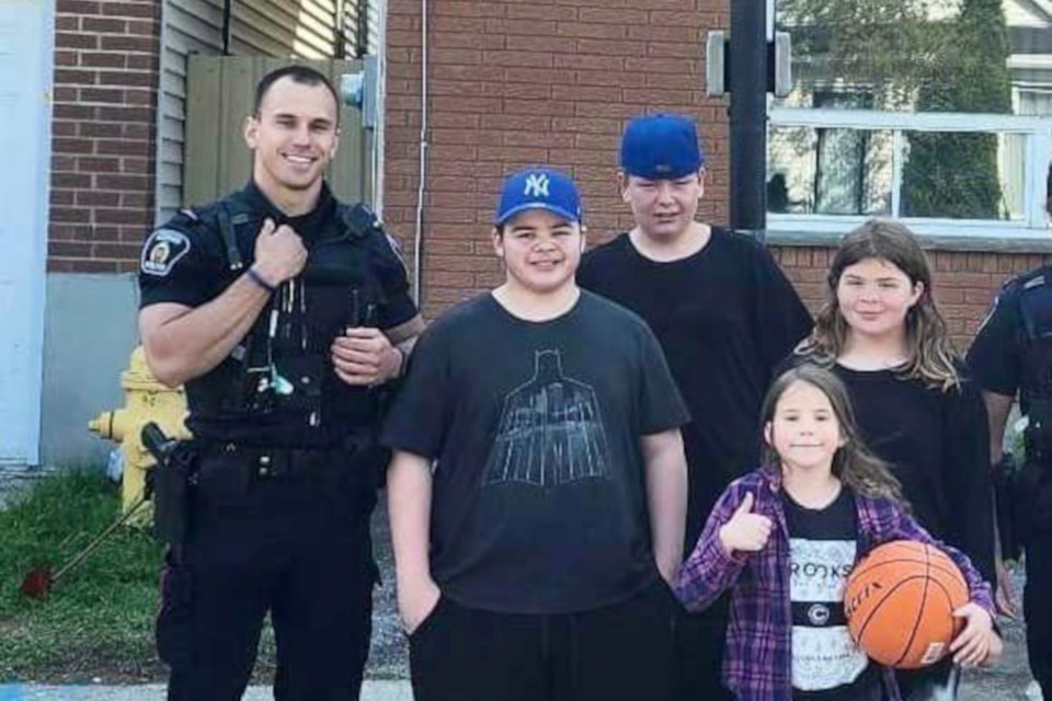Greater Sudbury police officers pose for a photo with children after playing some basketball with them on Sunday morning.