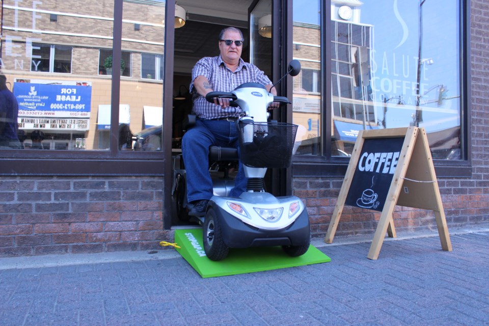 Passerby Gaston Tremblay became the first person to test Salute Coffee Company's new  StopGap accessibility ramp at its Elm Street entrance July 5. The ramp allows those in wheelchairs or mobility scooters to enter and exit the establishment effortlessly. (Callam Rodya/Sudbury.com)