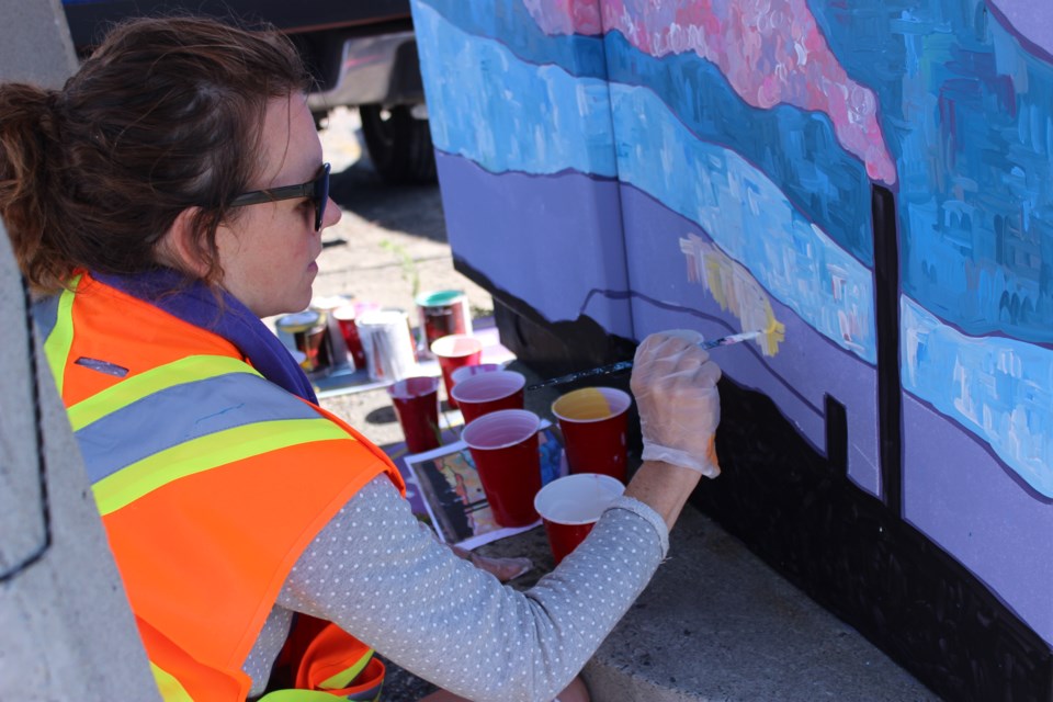 Artist Julieanne Steedman paints a utility box at the corner of Elgin and Minto Streets in Downtown Sudbury Aug. 3. Steedman is one of 24 local artists participating in the Up Here Urban Art + Music Festival's Power Up Project, which will see 24 downtown utility boxes used as canvases for new public art. (Callam Rodya/Sudbury.com)