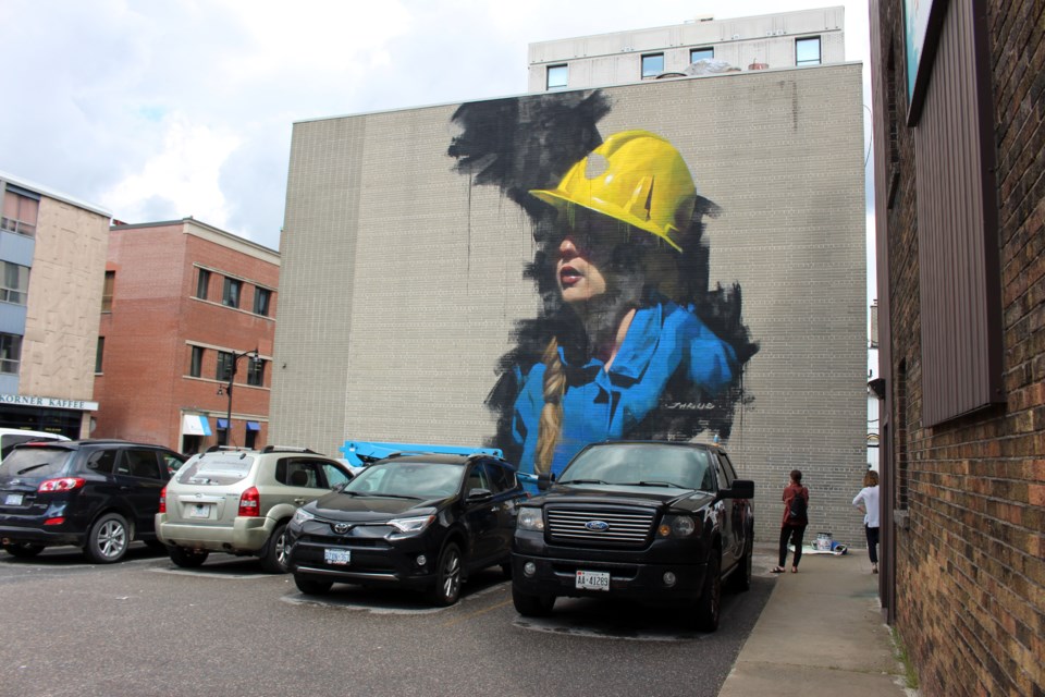 Internationally-renowned muralist Jarus pays tribute to his grandfather, who was a Sudbury miner, by painting this portrait of a female miner at the corner of Lisgar and Larch streets. The photo-realistic painting is just one of the art installments to hit Sudbury's downtown core as part of the Up Here festival that takes place 18-20. (Heather Green-Oliver/Sudbury.com)