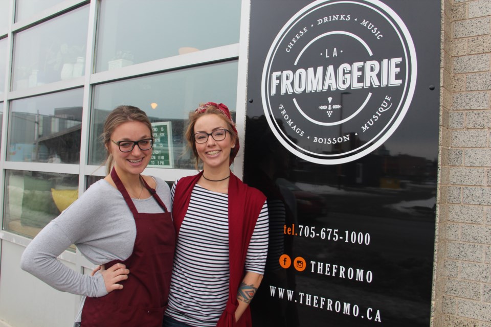 The ladies of the Fromo — Kelsey Cutinello and Valerie Fremlin — show off the new sign for La Fromagerie. (Heidi Ulrichsen/Sudbury.com)