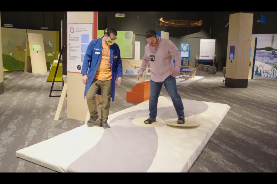 Waubgeshig Rice tries out some snowshoes with the help of Matthew Graveline at Science North's new exhibit, Indigenous Ingenuity: Timeless Inventions.