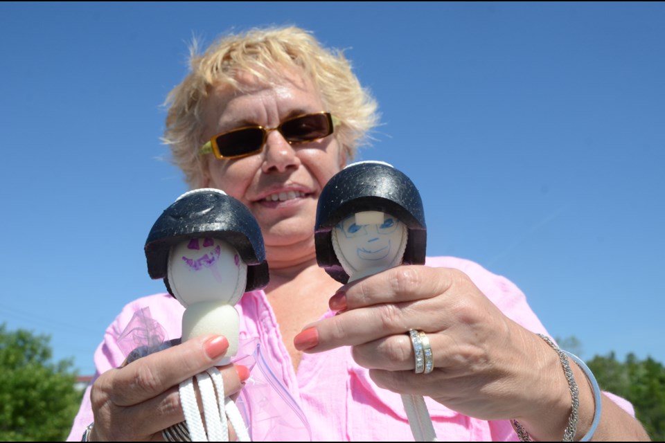 Julie Wilson, who sits on the board of directors for the Brain Injury Association, Sudbury District, uses Greg and Peggy Egg to demonstrate just how effective helmets can be in protecting the brain. Photo by Arron Pickard.