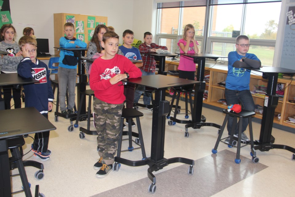 Grade 5 students at École publique de la Découverte demonstrate their classroom's standing desks. Photo by Heidi Ulrichsen.
