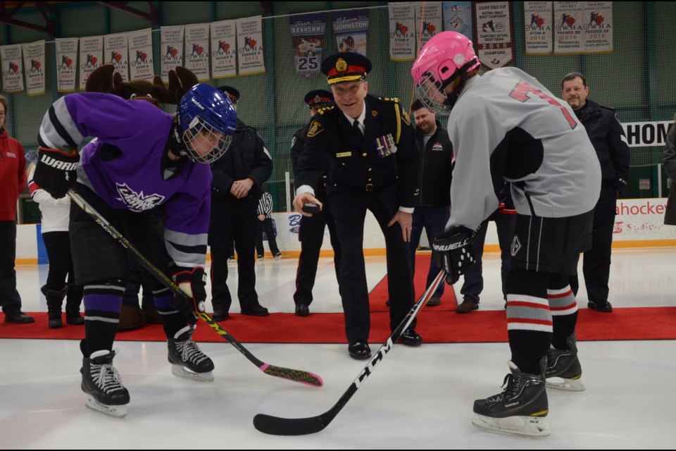 Greater Sudbury Police Chief Paul Pedersen performs a puck-drop ceremony to kick off the 2017 Police Cup hockey tournament at Gerry McCrory Countryside Arena. Fiona Simser, right, of the Cedar Park Redwings, and Lucas Black, left, of the LoEllen Lightning, also participated in the puck crop. Photo by Arron Pickard.