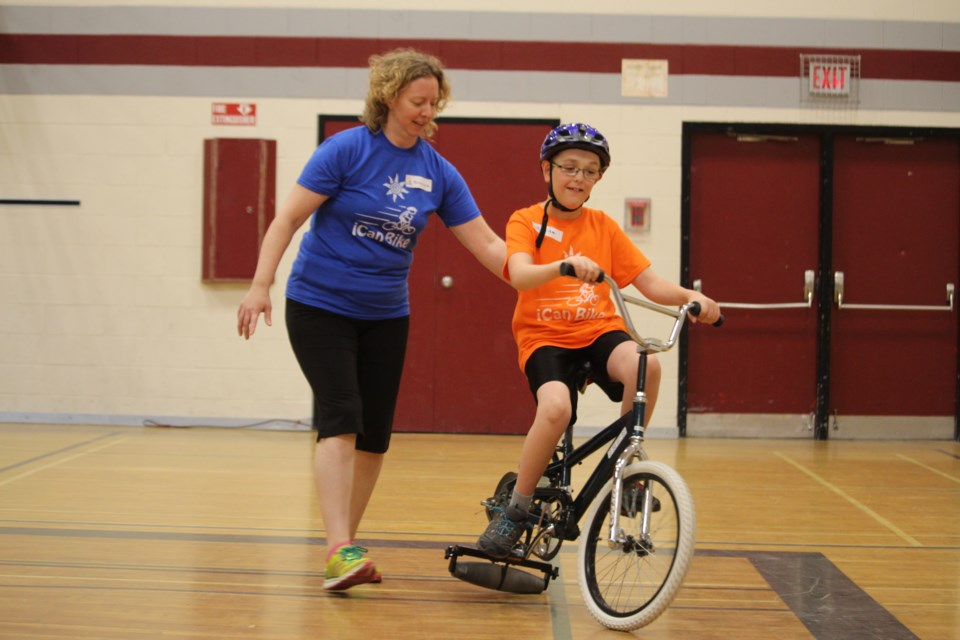 Liam MacIntyre, 10, learns how to ride a two-wheel bicycle with help from physiotherapist, Penny Jacob, at this year's iCan Bike Program, hosted by HSN’s NEO Kids Children’s Treatment Centre. (Heather Green-Oliver/Sudbury.com)