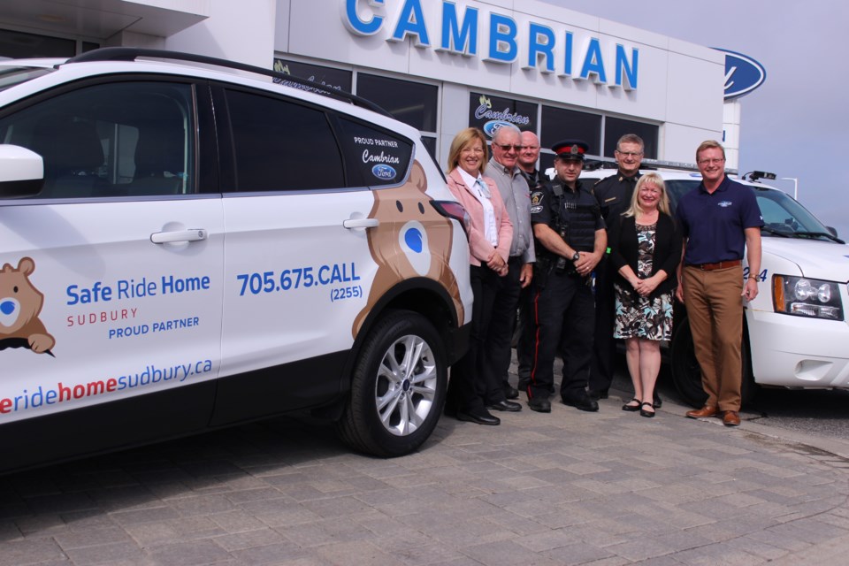 Sudbury Tim Hortons owners Marian and Gary MacKenzie, GSPS Sgt. Derick Rose, Const. John Coluzzi, Deputy Chief Al Lekun, Safe Ride Home Sudbury president Lesli Green and Cambrian Ford owner Scott McCulloch stand next to Safe Ride Home Sudbury's new branded vehicle. Formerly known as Operation Red Nose, the organization announced it has re-branded as Safe Ride Home Sudbury Aug. 10 at Cambrian Ford. The service has offered drivers a ride home in their own vehicles after a night of holiday celebrations in Sudbury for 18 years. (Callam Rodya/Sudbury.com)