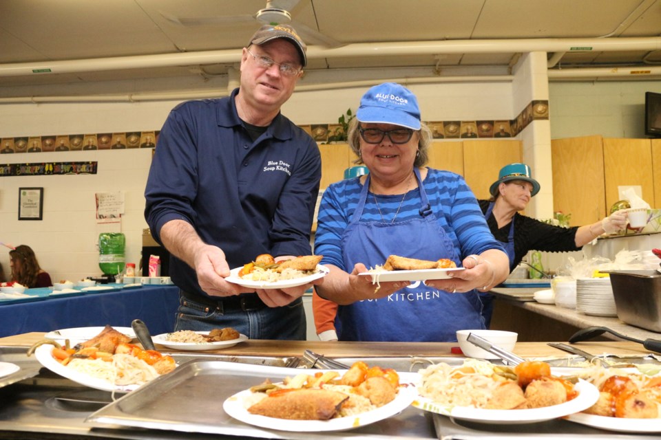 Blue Door Soup Kitchen volunteers Bill Hickey and Colleen Swanson dished out plates of Chinese food for the New Year's meal on Dec. 29. (Arron Pickard)