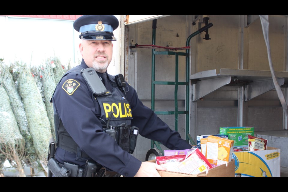 OPP Const. Andre Taschereau, helps carry food donations at the Cops for Christmas Food Bank Drive. (Gia Patil)