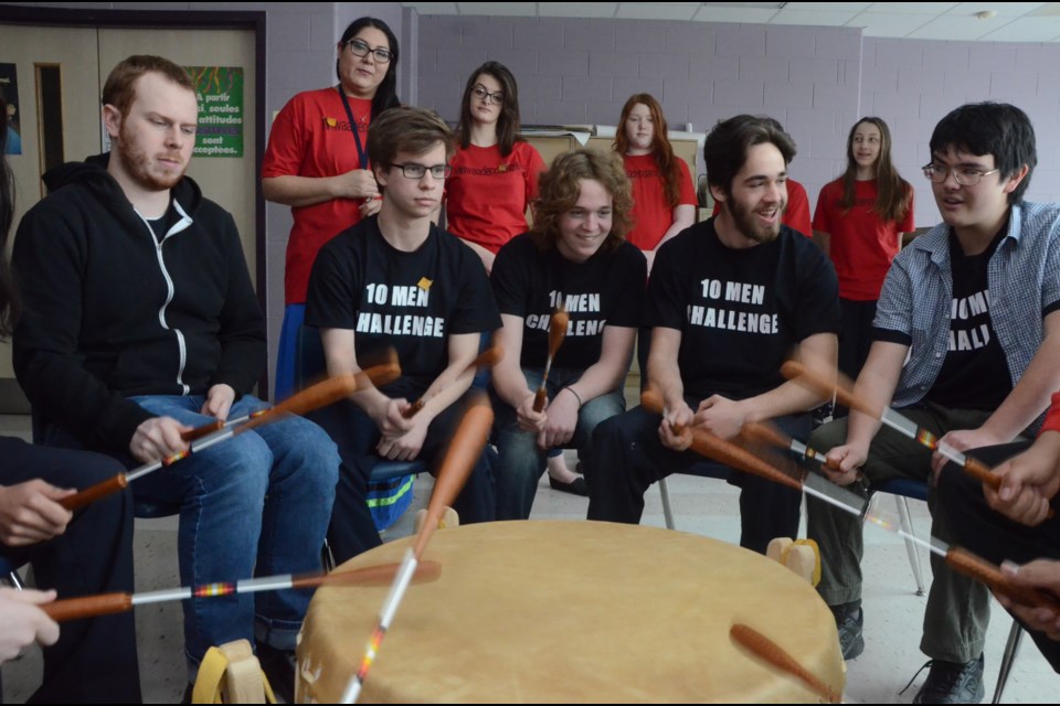 Participating in a drumming circle during the Ten Men Challenge on Thursday are, from left, Doug Lowe, Tanner Talbot, Ben Paquette, Matthew McDonald and Zach Vallely. Looking on in the background is Indigenous support worker Carla Petahtegoose, and students helpers Rylee Vellow, Hannah Depatie, Isabelle Focault (hidden by Matthew McDonald) and Adrielle Bourret.  (Arron Pickard)