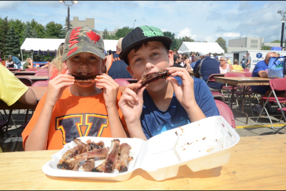 Brothers Kyle Buckland, 9, and Liam Buckland, 12, polish off what's left of their ribs when they visited Ribfest with their dad, Kevin Buckland. (Arron Pickard)