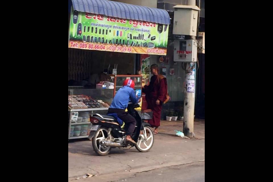 Buddhist monk receives his morning alms donation of food – on the street in Battambang. (Suzanne Harvey)