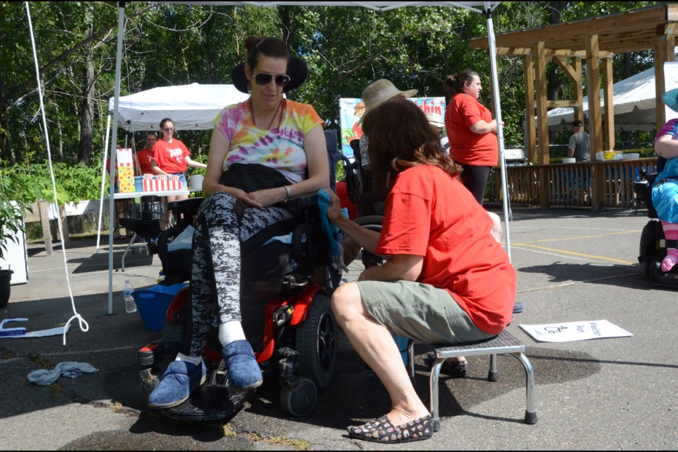 ICAN client Elizabeth Kerstens gets her wheelchair washed by Carmen Sampson, manager of client services, during ICAN's 40th anniversary celebration. (Arron Pickard/Sudbury.com)