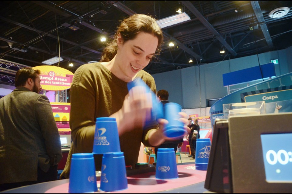 Science North science communicator Arielle Dufresne tries her hand at stacking cups, one of the interactive exhibits that are part of The Science of Guinness World Records. (Arron Pickard/Sudbury.com)