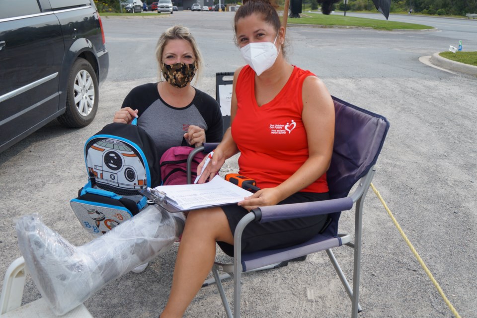 Melanie Pelletier of Brady Storage and Lynne Ethier of Our Children, Our Future Sudbury hand out backpacks to disadvantaged families - and Ethier even does it with a cast on.            