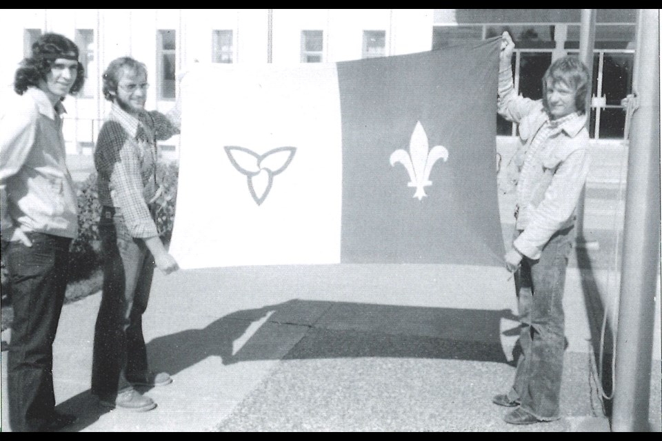 Flag co-creators Yves Tassé (centre) and Michel Dupuis (right) pose with the newly created flag, Sept, 25, 1975.