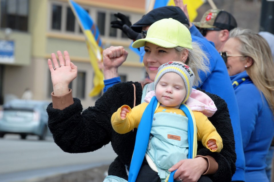 Tracy Blais and her daughter, Desiree, 18 months, wave at people on Notre Dame Avenue during today’s rally for Ukraine. Tracy said that her great-grandfather is from Ukraine and she wanted to show her support. 