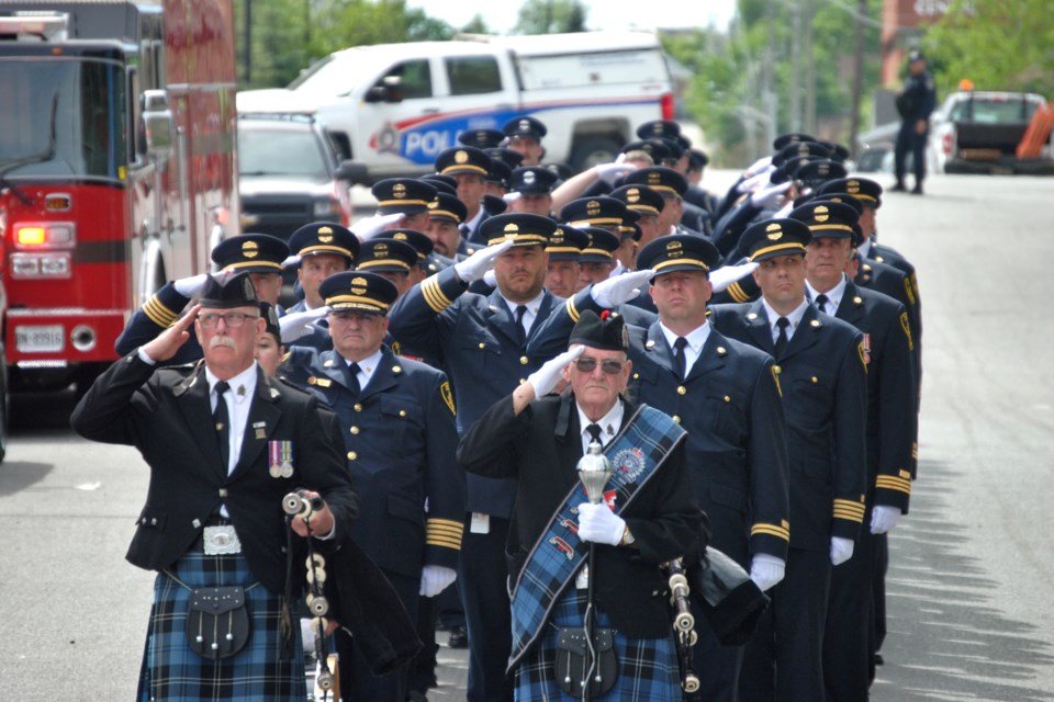 Greater Sudbury emergency responders salute as pallbearers carry the coffin of first-class firefighter Mike Frost to a waiting hearse outside of Church of Christ the King earlier today.