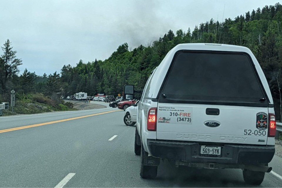A lineup of traffic is seen backed up along Highway 144, with smoke seen billowing on the horizon. 
