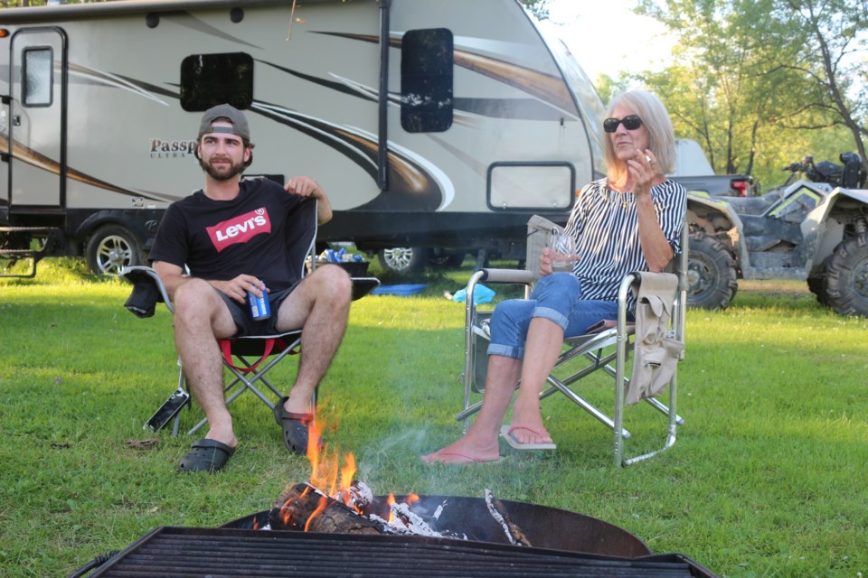 Brinley Finch sits by a campfire with his grandmother, Beverly McNab, at Whitewater Lake Park in Azilda earlier this week. Finch is from Marmora, and is a seasonal camper in order to be closer to his work in Greater Sudbury. 