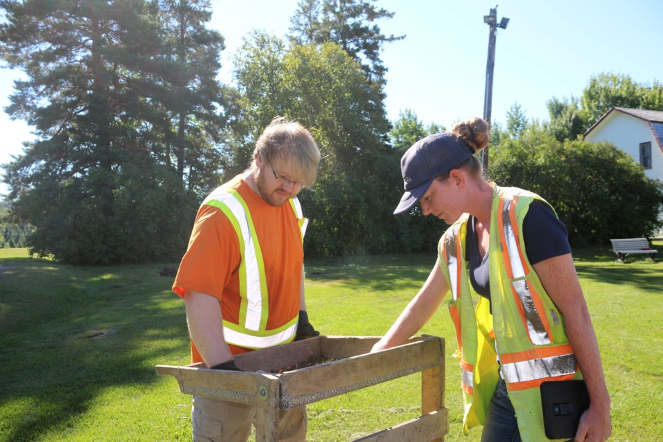 Owen Sound-based archaeologists Ryan Douglas (field tech) and Hailey Buckton (field director) from Archaeological Research Associates look over a sift of soil at Anderson Farm Museum in Lively on Friday. 
