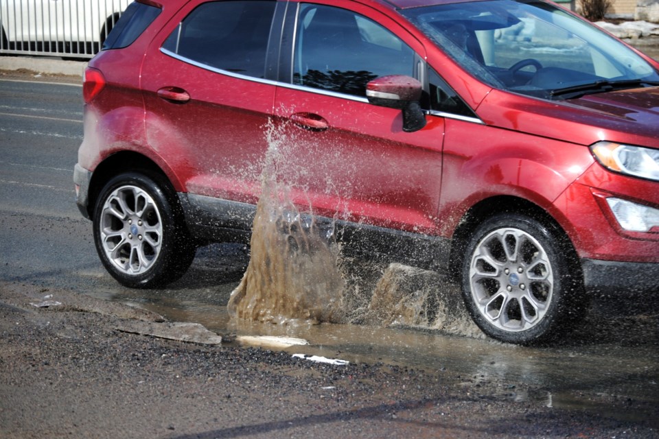 A vehicle is seen splashing through a pothole on Elm Street last spring.