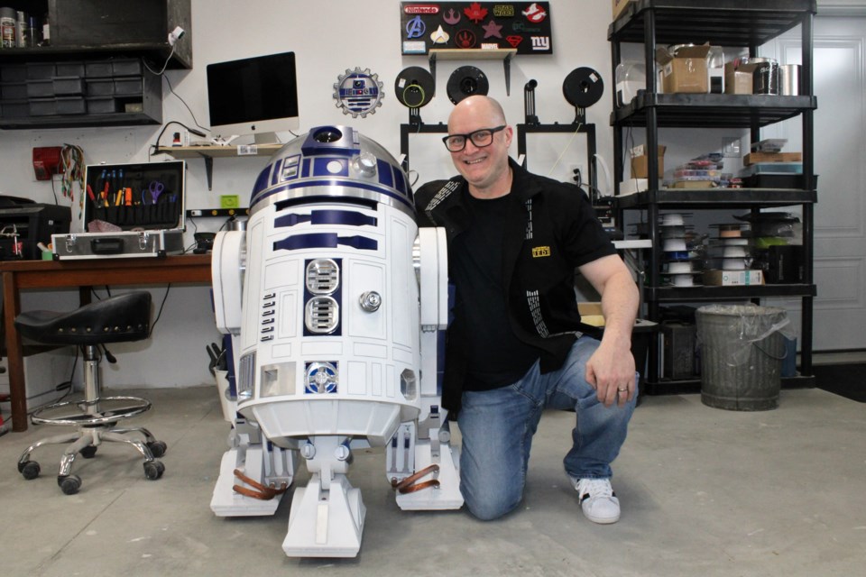 Robert Cast is seen with the R2-D2 replica he created at his Hanmer garage workspace.
