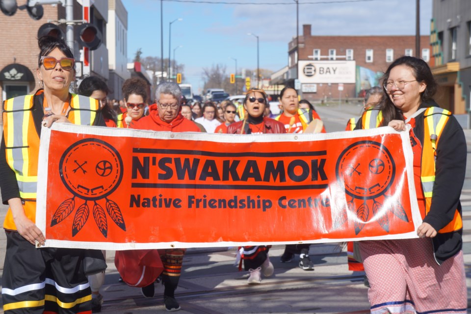 (Right, holding sign) Autumn Lewis, healing and wellness co-ordinator for the N’Swakamok Native Friendship Centre, leads the walk through the downtown core of Sudbury. 