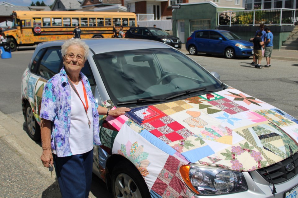 Eileen Thompson is seen with the Capreol Needlework Club’s Quilt-Mobile, which she fashioned over a couple of days by sewing together members’ incomplete quilt portions.
