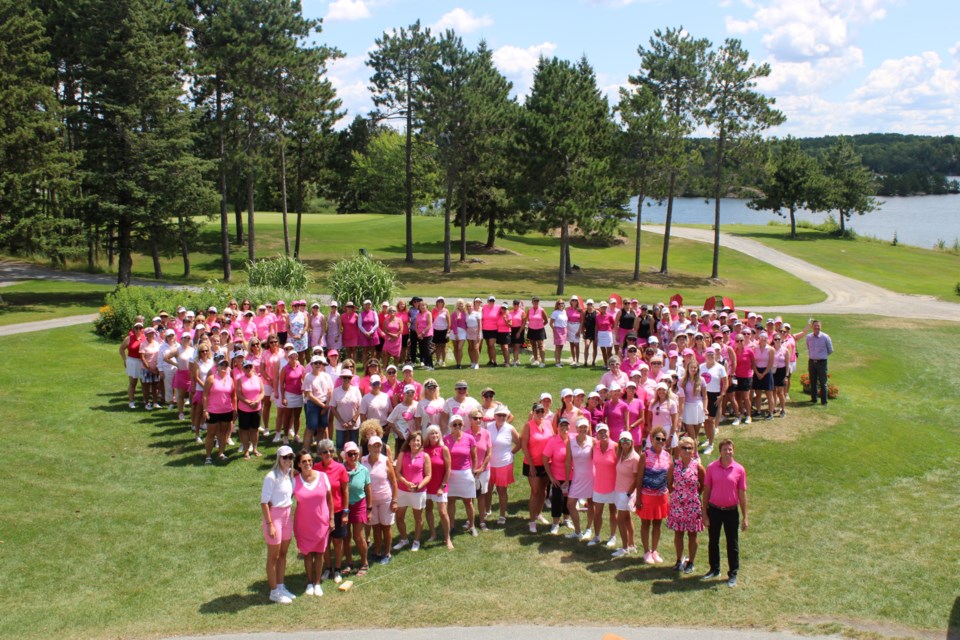 Think Pink golf tournament participants line themselves up into the shape of a pink ribbon during Tuesday’s event at Idylwylde Golf and Country Club.

