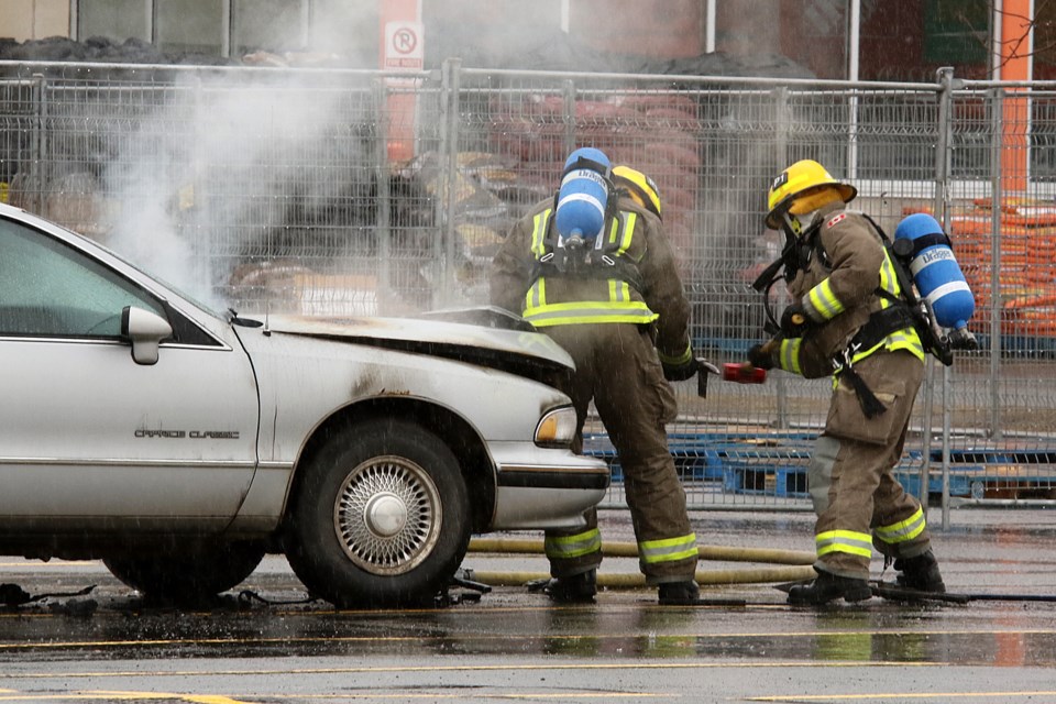 Firefighters attempt to open the hood of a vehicle on fire in the parking lot of Thunder Bay's Home Depot outlet (Leith Dunick, tbnewswatch.com). 