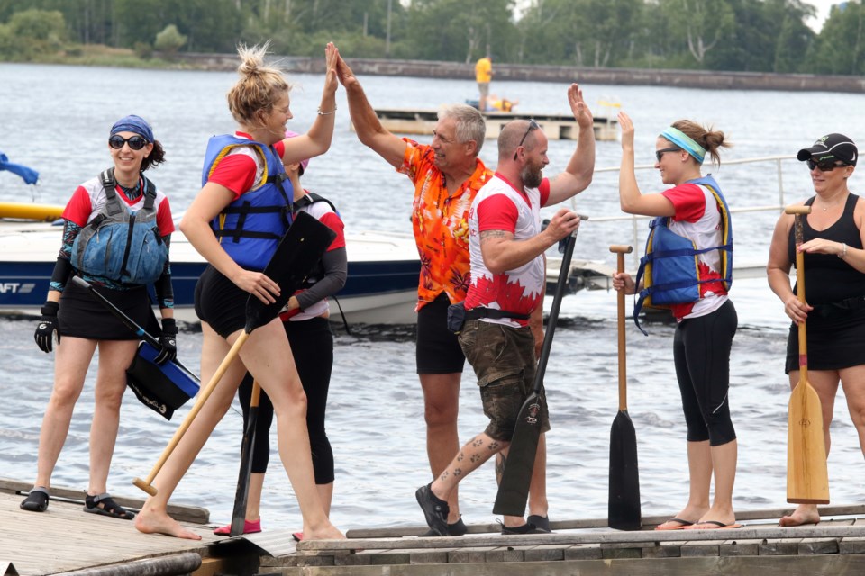 Volker Kromm (centre/orange shirt) handed out high-fives at the Dragon Boat festival at Boulevard Lake in August 2017 (Tbnewswatch file)