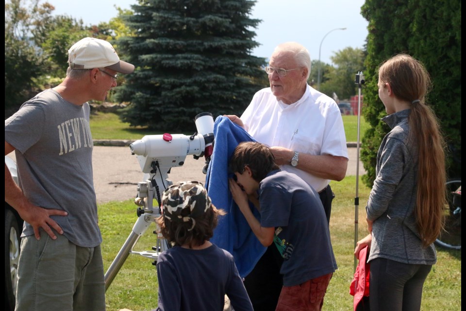Father Francisco, a member of like Thunder Bay Centre of the Royal Astronomical Society, shares his telescope with Richard Sherlock and his children, Timothy, Benjamin, and Abigail. 