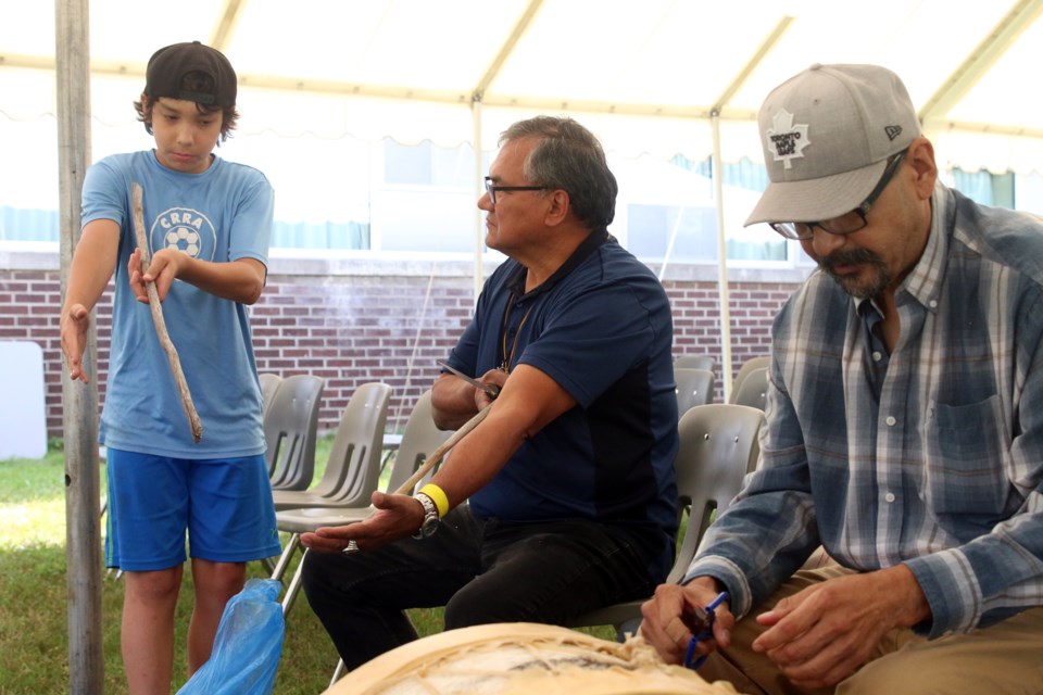 Bobby Yoki, 13, learns how to build a traditional drum stick from elders Bob Baxter and Marcel Bananish during the Mino Bimaadiziwin program. 