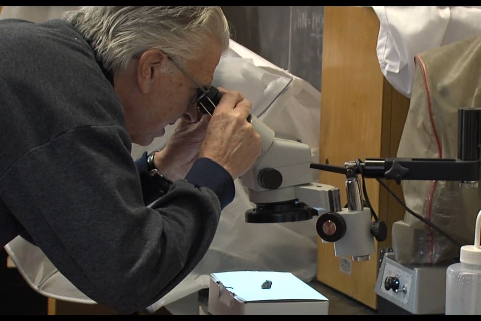 Stephen Kissin, a geology professor at Lakehead University examines fragments collected from a possible meteorite strike on Highway 61 on Dec. 13. (Jonathan Wilson - TBT News). 