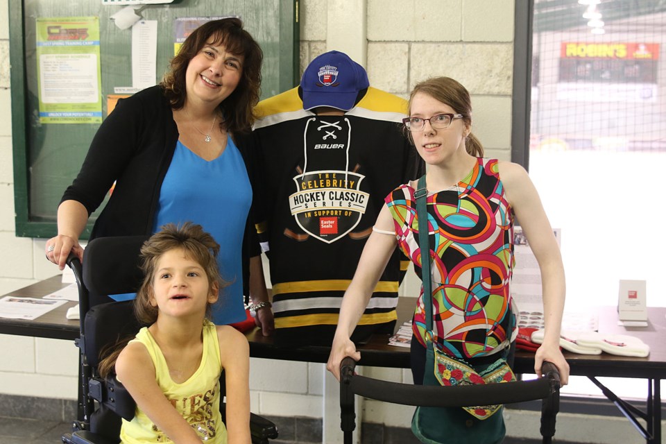 Rhonda Harrison, (left, blue shirt), Kamryn Pilkington, and Kendal Douglas posing in fornt of a Celebrity Hockey Classic Jersey at the Tournmanet Centre where the event will be held on October 20. (Michael Charlebois, tbnewswatch.com)