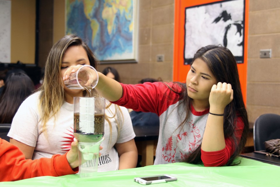 Tyra Quewezance of Wabaseemoong Independent Nations (left), and Ashley King of Gull Bay First Nation work on their hand-made filtration system at Lakehead Univeristy. (Michael Charlebois, tbnewswatch,com)