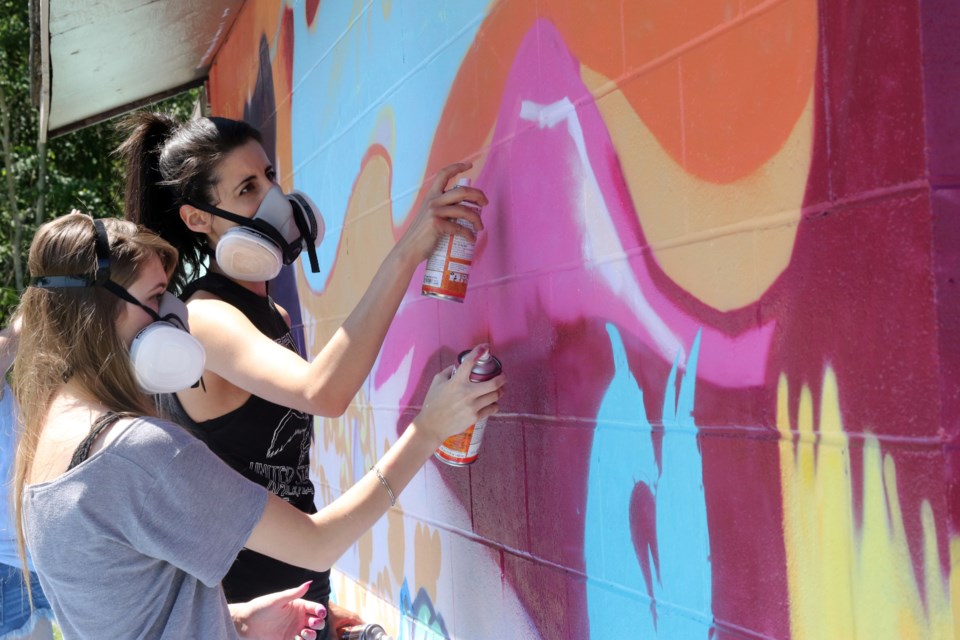 Local artists Mary McPherson (left) and Liz Buset working on the mural at the top of Mt. McKay. (Michael Charlebois, tbnewswatch.com)