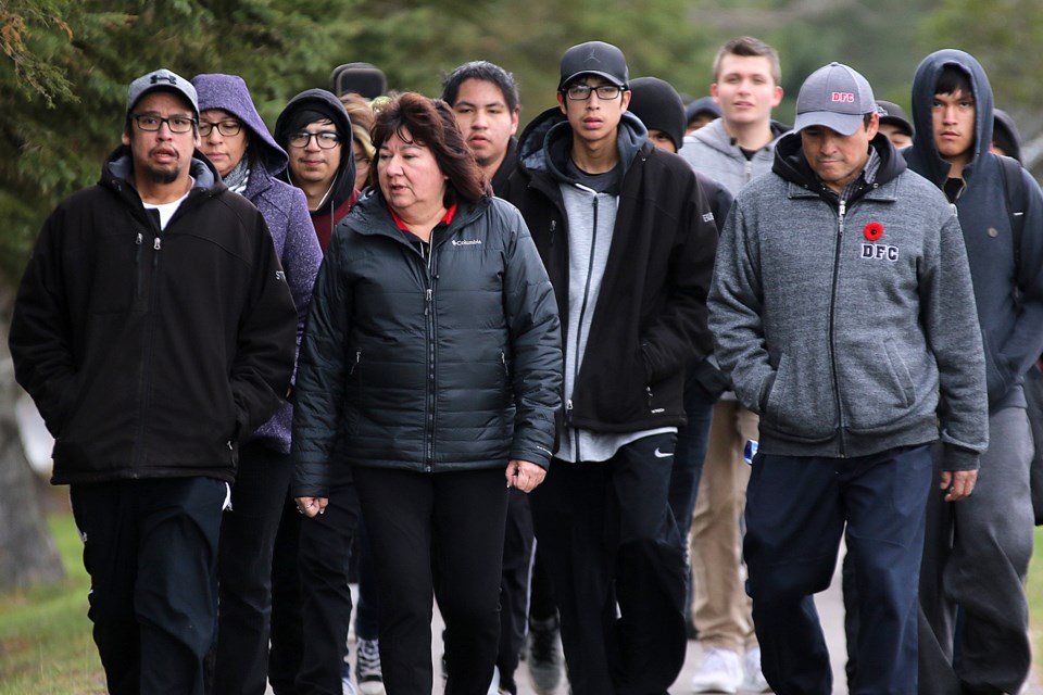 Ricki Strang (far left) walks with students, family and supporters along a path adjacent to the Neebing McIntyre Floodway on Nov. 1, 2017, marking the 10th anniversary of the recovery of the body of his brother Reggie Bushie from the river (Leith Dunick, tbnewswatch.com). 