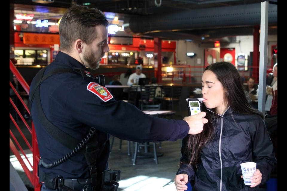 Const. Mark Cattani administers a demonstration breathalyzer test to fist year nursing student, Meagan Pawlicki, during the launch of the new impaired driving campaign at Lakehead University.  