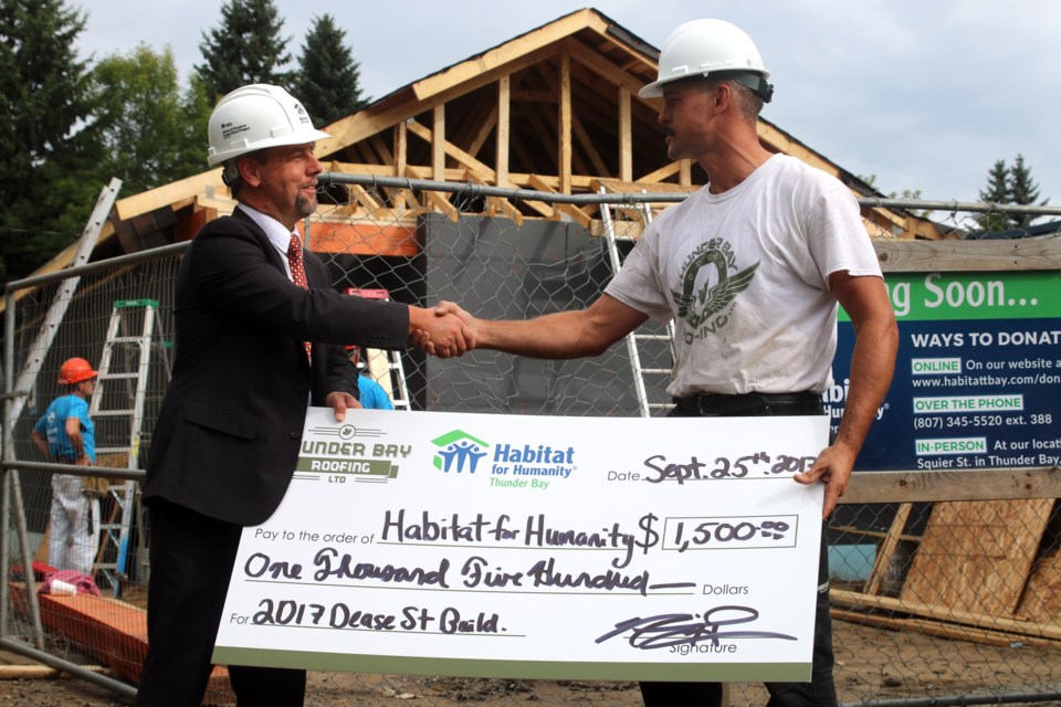 Neil Hrabowy (right), owner of Thunder Bay Roofing, donates $1,500 to Habitat for Humanity Thunder Bay, in addition to providing the roof on its 2017 build. 
