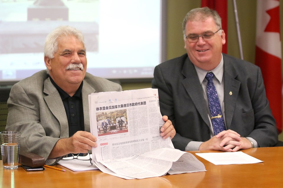 Coun. Joe Virdiramo (left) and city manager Norm Gale showcase a Chinese newspaper that detailed their Sister City visit to Jiaozuo, China. (Leith Dunick, tbnewswatch.com). 