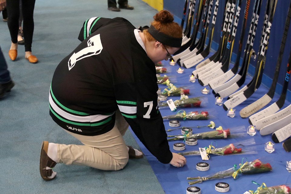 A woman on April 12, 2018 lays a puck at a memorial honouring the victims of the deadly April 6 crash that killed 16 members of the Humboldt Broncos Junior A hockey team in northern Saskatchwan. (Leith Dunick, tbnewswatch.com)