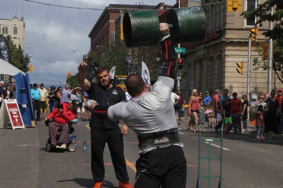 Jared Wick competes in the circus dumbbell in front of a crowd on Cumberland Street (Michael Charlebois, tbnewswatch)
