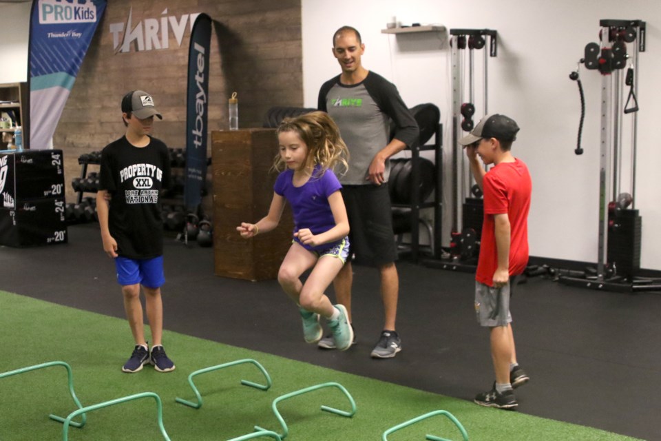Tyler Garatti, 12, brother Lucas, 10, and sister Zoe, 8, work out on Wednesday, July 4, 2018 at Thrive Strength and Wellness while Paul Hemsworth looks on. (Leith Dunick, tbnewswatch.com)