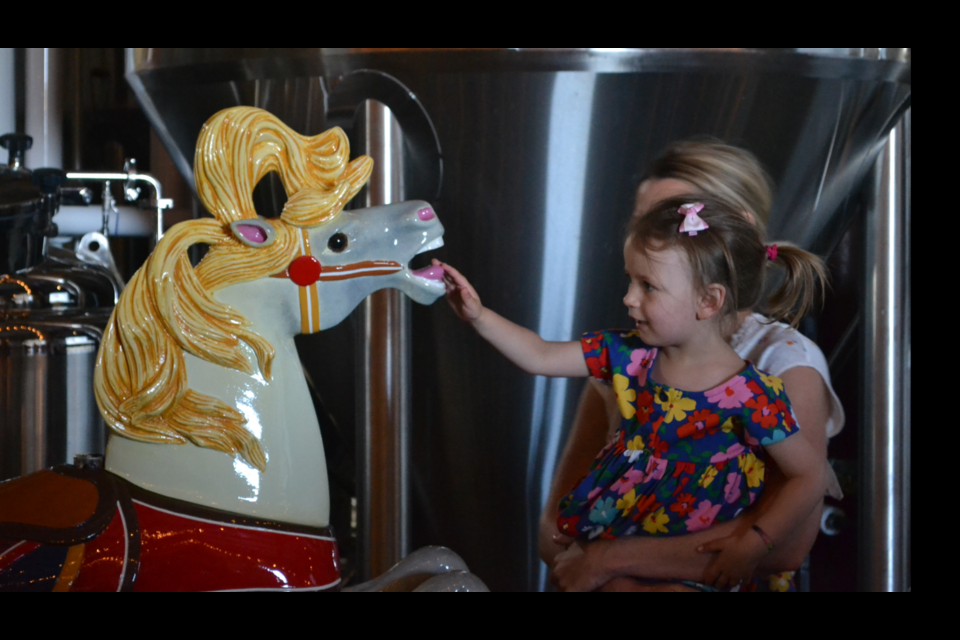 Karen and Ed Fukushima's granddaughter admires the restored horse. (Photo courtesy of Kate Beaulieu)