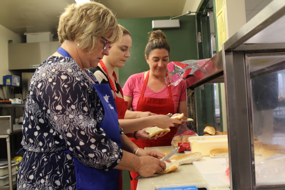 Volunteers Susan Childs (front), Danielle Ritchie, and Susan Childs make sandwiches at the Shelter House. (Michael Charlebois, tbnewswatch)