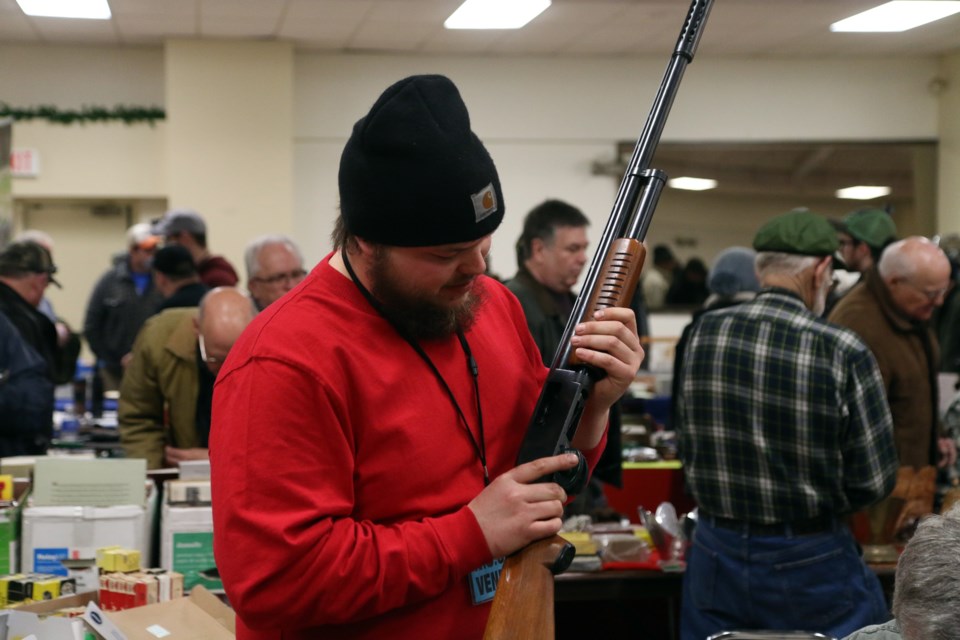 Scott Gushulak with Great Northern Gun Works, inspects a shotgun during the New Ontario Shooters Association Gun Show on Saturday. 