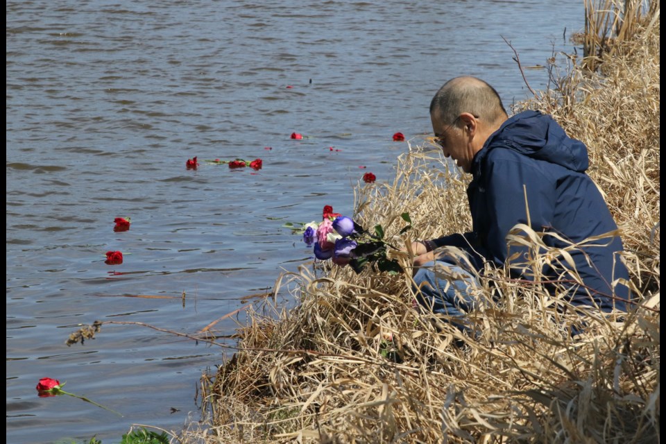 Mike McKay laying roses onto McIntrye River at the same location where his grandson, Josiah Begg, was found one year ago. (Michael Charlebois / tbnewswatch)
